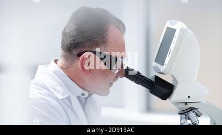 close up. scientist looking carefully through a microscope. Stock Photo