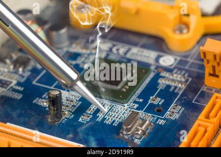 use a soldering iron to solder the electronic part to the Board. Computer repair. Macrophotography. Stock Photo