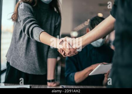 young staff in protective masks shaking hands with each other. Stock Photo