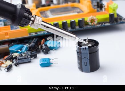 soldering iron on the background of a computer Board and capacitors in soft focus. The concept of repair and service Stock Photo