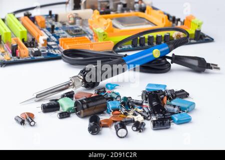 soldering iron on the background of a computer Board and capacitors in soft focus. The concept of repair and service Stock Photo