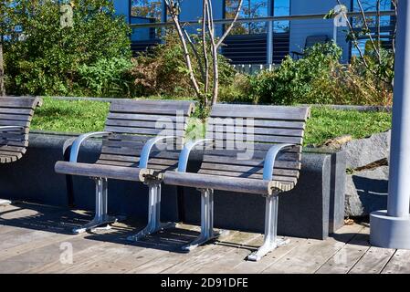 Two armchairs, made of metal and weathered wood, are arranged side by side in a park in Williamsburg, Brooklyn, NY Stock Photo