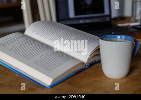 Multitasking reading drinking coffee working on laptop Stock Photo