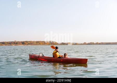 Man with a dog in a canoe on the lake. Young male person with spaniel in a kayak row boat, active free time with pets, companionship, adventure dogs Stock Photo