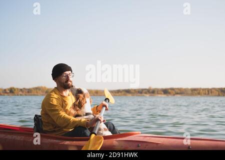 Man with a dog in a canoe on the lake. Young male person with spaniel in a kayak row boat, active free time with pets, companionship, adventure dogs Stock Photo