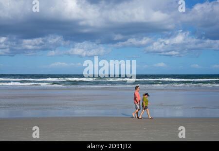 A couple walks on the shore in Daytona Beach, FL. Stock Photo