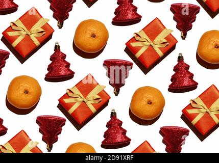 Pattern from tangerines, shiny red toys in the form of a Christmas tree and a gift on a white background. Wrapping paper Stock Photo