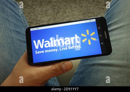 Man holding smartphone with Walmart retail corporation logo Stock Photo