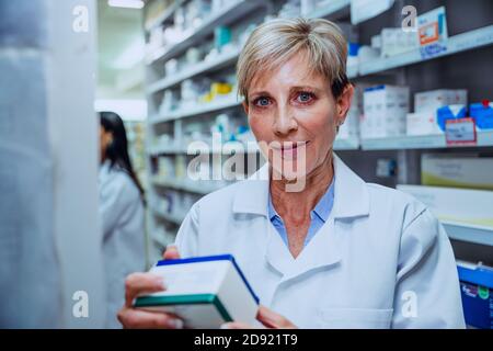 Female caucasian pharmacist checking labels of medication before selling it to patients  Stock Photo