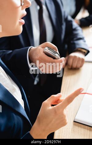 cropped view of correspondent with dictaphone interviewing politician pointing with finger during press conference on blurred background Stock Photo
