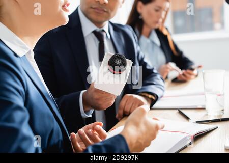 partial view of indian journalist with microphone interviewing politician during press conference on blurred background Stock Photo