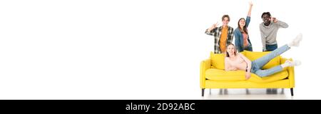 Panoramic shot of cheerful multiethnic teenagers showing peace sign near yellow couch on white background Stock Photo