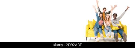 Panoramic shot of cheerful multicultural teenagers showing hello gesture at camera on couch on white background Stock Photo
