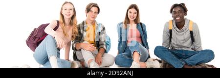 Panoramic shot of positive teenagers with backpacks sitting on white background Stock Photo