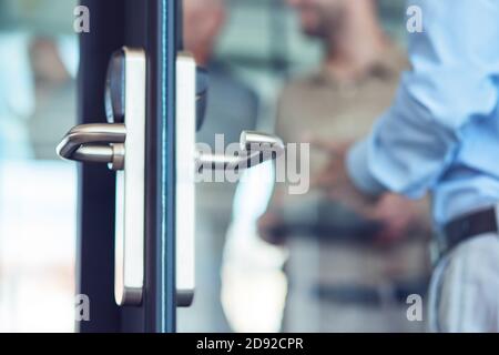 Businessman entering at work, opening glass door in the modern office, selective focus Stock Photo