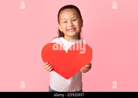 Asian little girl holding paper heart in hands Stock Photo
