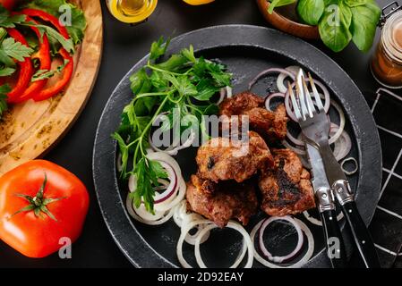 Traditional georgian dish shish kebab or shashlik, grilled pork meat served with braised eggplants, pepper and tomatoes.