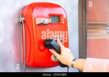 a woman's hand dials a phone number on a public pay phone Stock Photo