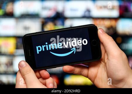 A teenager watching Amazon Prime Video on a mobile phone and computer Stock Photo