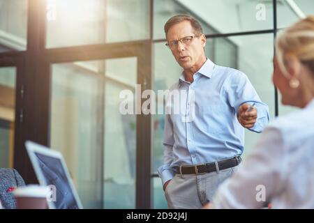 Focused mature businessmen discussing something with female colleague while working together in the modern office Stock Photo
