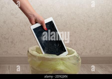 Woman throws it in the litter bin modern tablet with highly broken screen Stock Photo