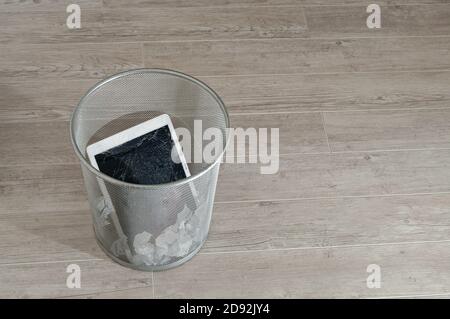 Modern tablet with highly broken screen in the litter bin Stock Photo