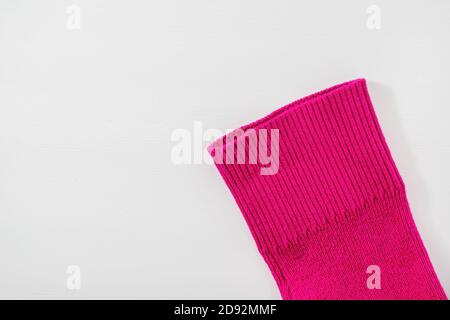 Part of the sleeve of pink knitted sweater on a white wooden background. Top view, copy space for text. Stock Photo