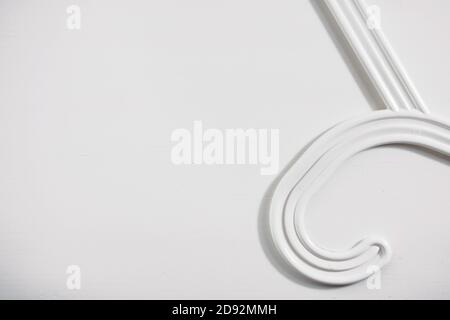 Part of a white clothes hanger on a white wooden background. Top view, copy space for text Stock Photo