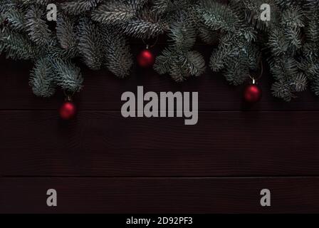 christmas tree twigs with red baubles on dark wood background Stock Photo