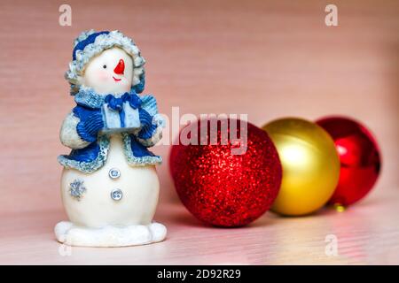 Christmas toys, ceramic snowman and tree balls on beige background. Selective focus Stock Photo