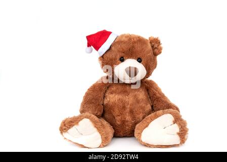 Funny teddy bear with small shiny Santa Claus hat on white xmas Stock Photo
