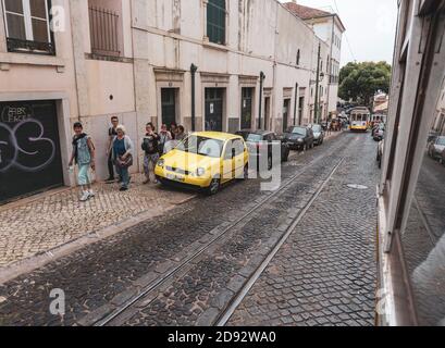 Lisabon/ Portugal-May 31st, 2017: People waving at passengers in popular tourist attraction-yellow tram number 28 in Lisbon streets Stock Photo