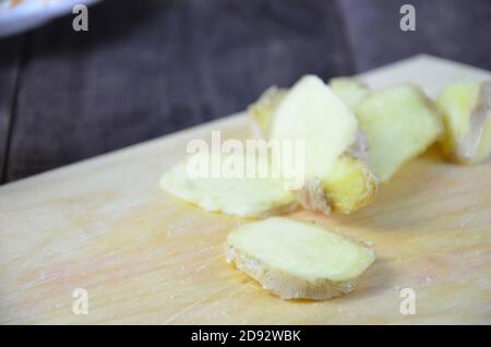 Ginger on cutting board, jar of honey, dried lemon slice, cinnamon and grater on kitchen table. Selective focus. Stock Photo