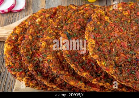 Traditional delicious Turkish foods; Lahmacun (Turkish pizza). Lahmacun traditional Turkish pizza and wraps with salad isolated on rustic wooden table Stock Photo