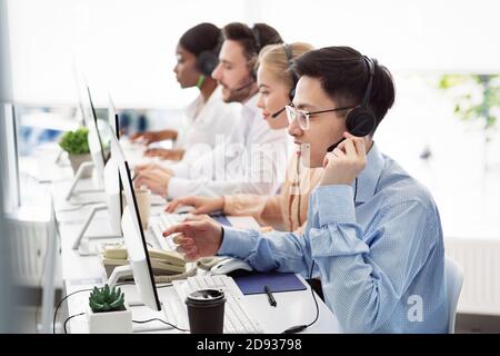 Telecommunications concept. Positive hotline consultants selling goods or services at call centre Stock Photo