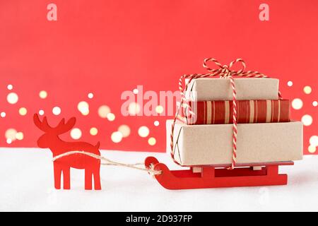 Toy reindeer and sleigh delivering christmas gifts on festive red background. Stock Photo