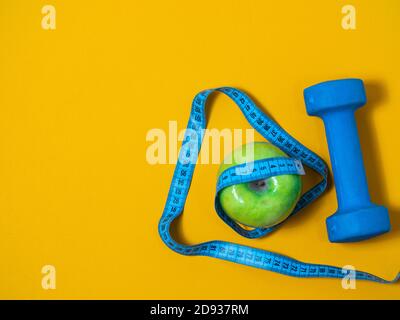 Top view of yellow soft measuring tape. Minimalist flat lay image of tape  measure with metric scale over turquoise blue background with copy space.  Stock Photo