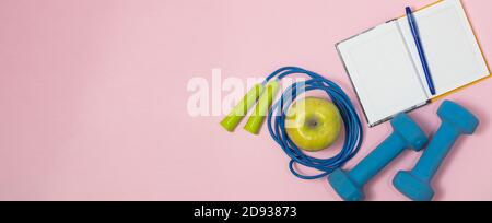 Fitness concept banner with dumbbells, jump ropes and measuring tape on a pink background. Stock Photo