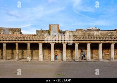 Tourists walking between the columns outside the Stabian Baths (Terme Stabiane) bathhouse, ancient Roman bath complex ruins, Pompeii, Campania, Italy Stock Photo