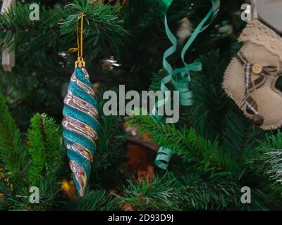 Toys on the Christmas tree city close-up. Glowing Christmas tree with gifts, balls and garlands. Christmas tree closeup for postcard. Stock Photo