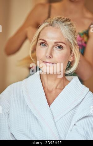 Portrait of beautiful middle aged caucasian woman at spa resort with cosmetologist on background. Beauty, skincare and cosmetology concept Stock Photo