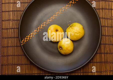 Baked apples with cinnamon in a ceramic bowl on a bamboo mat Stock Photo