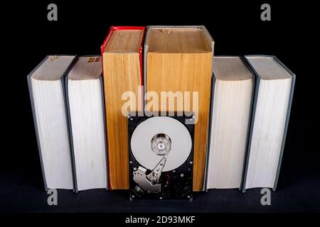 Old paper books and computer disk. Paper and digital data carrier. Dark background. Stock Photo