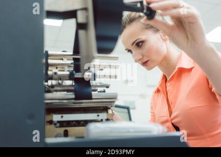 Worker woman putting new labels in printing machine Stock Photo