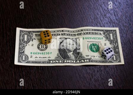 One dollar banknote and two dice lying on the table. Stock Photo