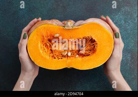 Woman holding fresh half of pumpkin. Seasonal vegetable. Stock Photo