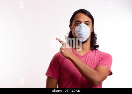 Young happy latin man with medical mask on white background. Copy space. Coronavirus concept. Stock Photo