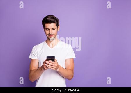 Portrait of his he nice attractive cute focused guy using digital device sending sms free time isolated over bright vivid shine vibrant violet lilac Stock Photo