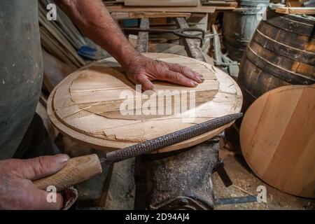 Production of wooden wine barrels. The master makes a wooden jars and barrels for wine.  Oak boards compresses them with iron rings Stock Photo