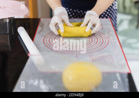 Womens hands roll out the pumpkin bread dough on kitchen table. Stock Photo